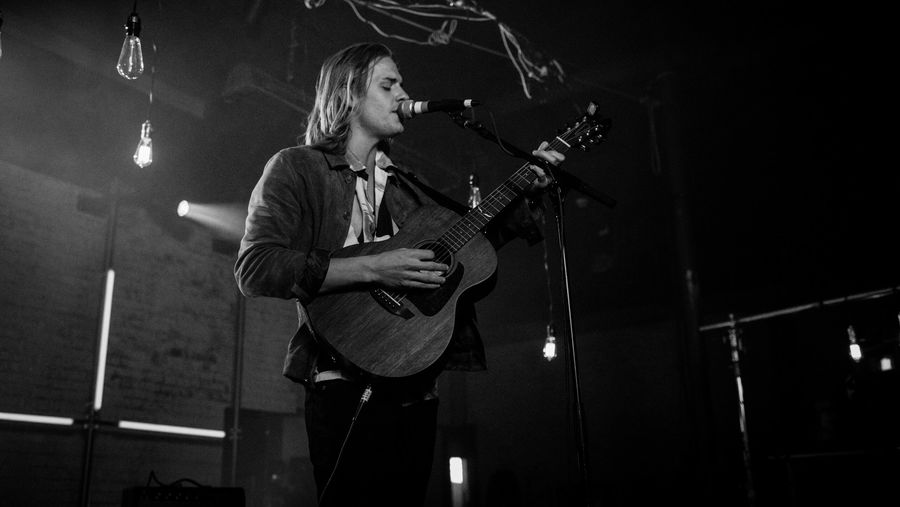 Schwarz-weißes Foto von Corey Harper der während unserer neuen LA Sessions singt und Gitarre spielt.
