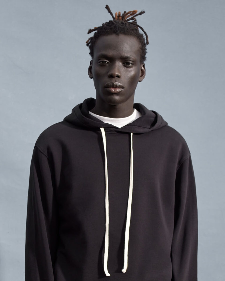 Portrait of a man wearing a black hoodie over a white t-shirt.