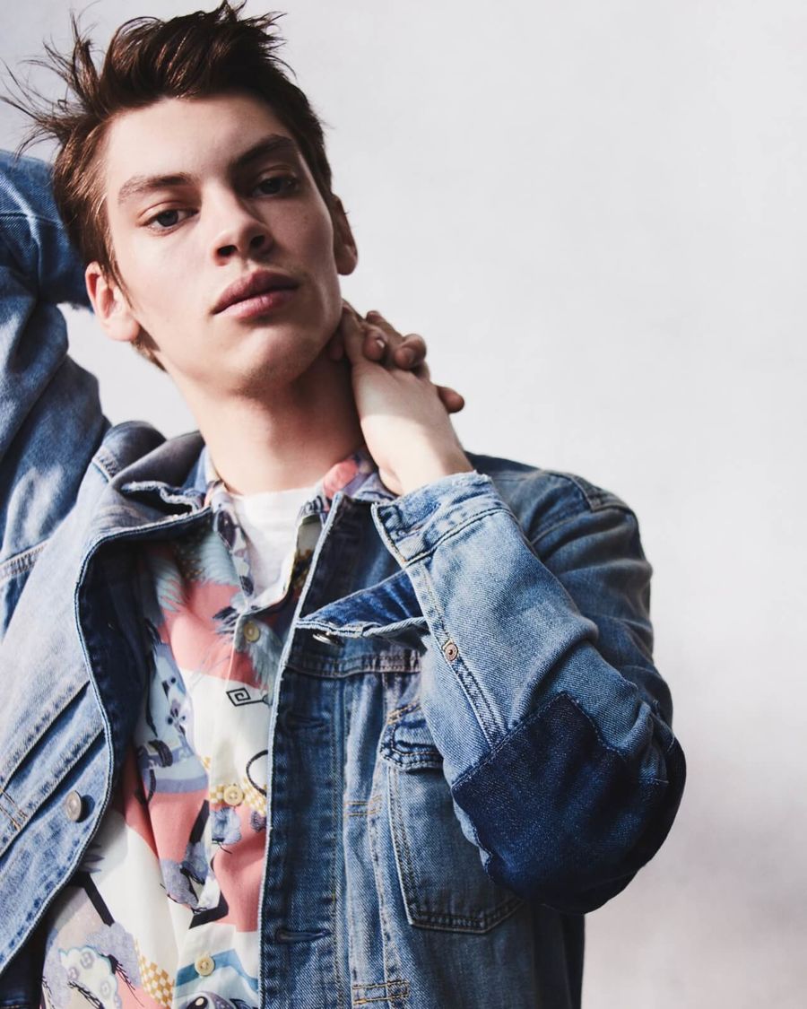 Portrait of a man wearing a denim jacket with a printed Hawaiian shirt and white t-shirt.