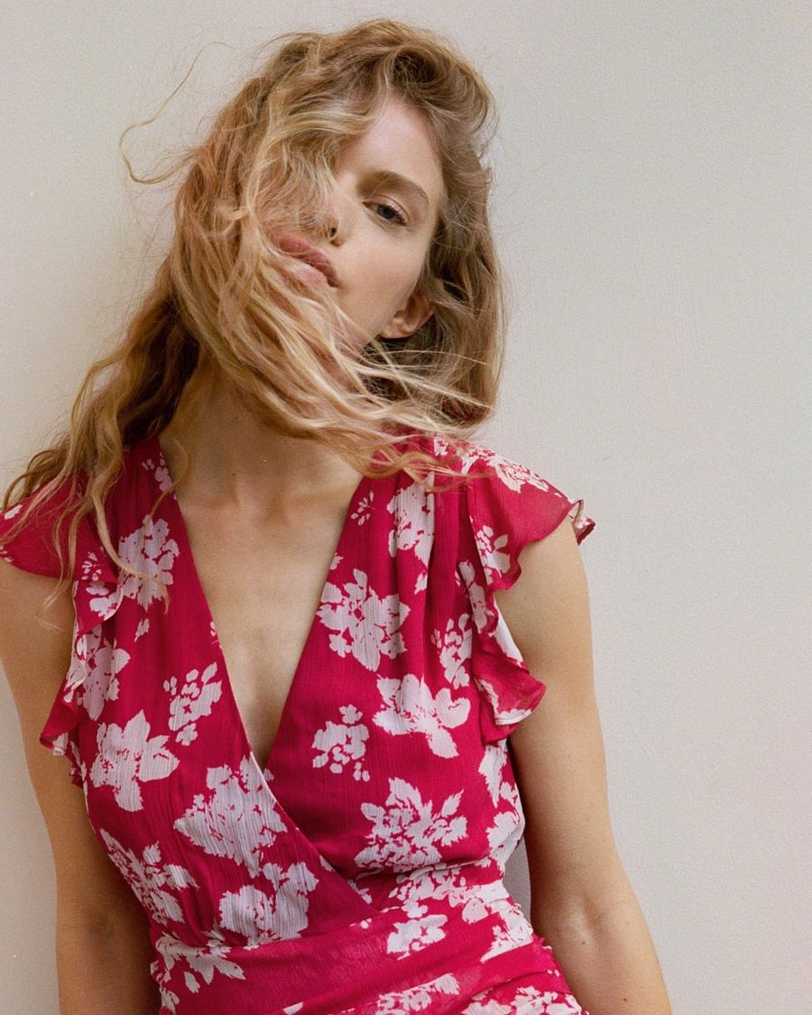 Portrait d'une femme portant une robe rouge à fleurs blanches.