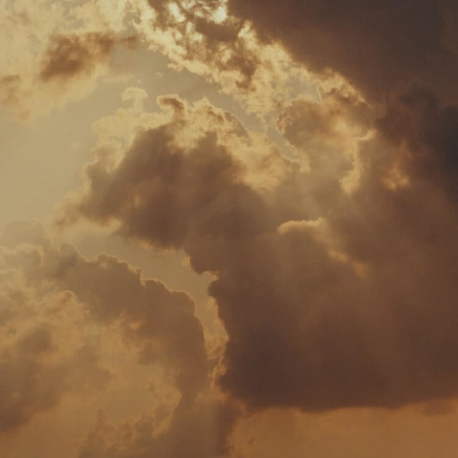 Photo of the sun peaking through dark clouds.