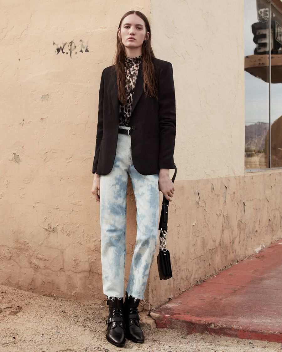 Image of a woman wearing a leopard printed top with a black blazer, acid washed denim jeans and black leather boots.