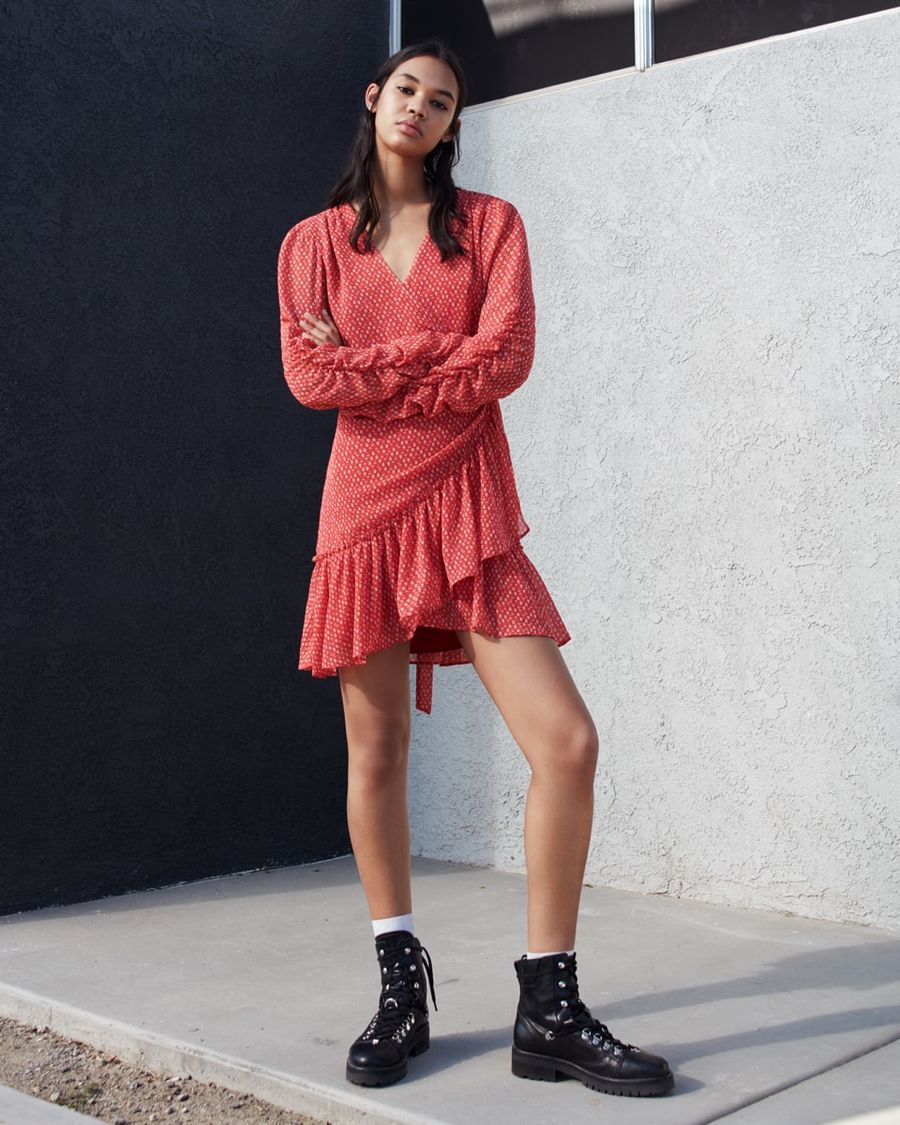 Woman wearing a red and white heart-printed dress with black leather boots.