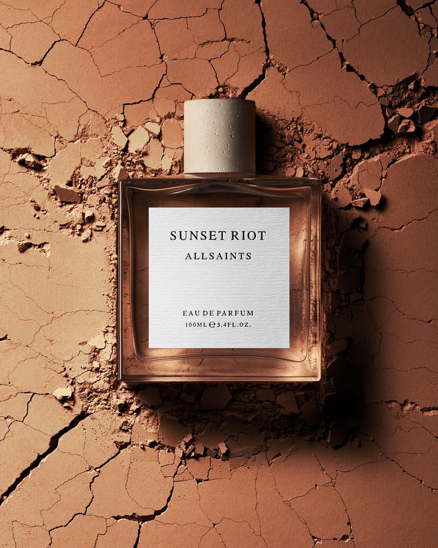Product shot of the Sunset Riot perfume bottle on an earthy ocre background.